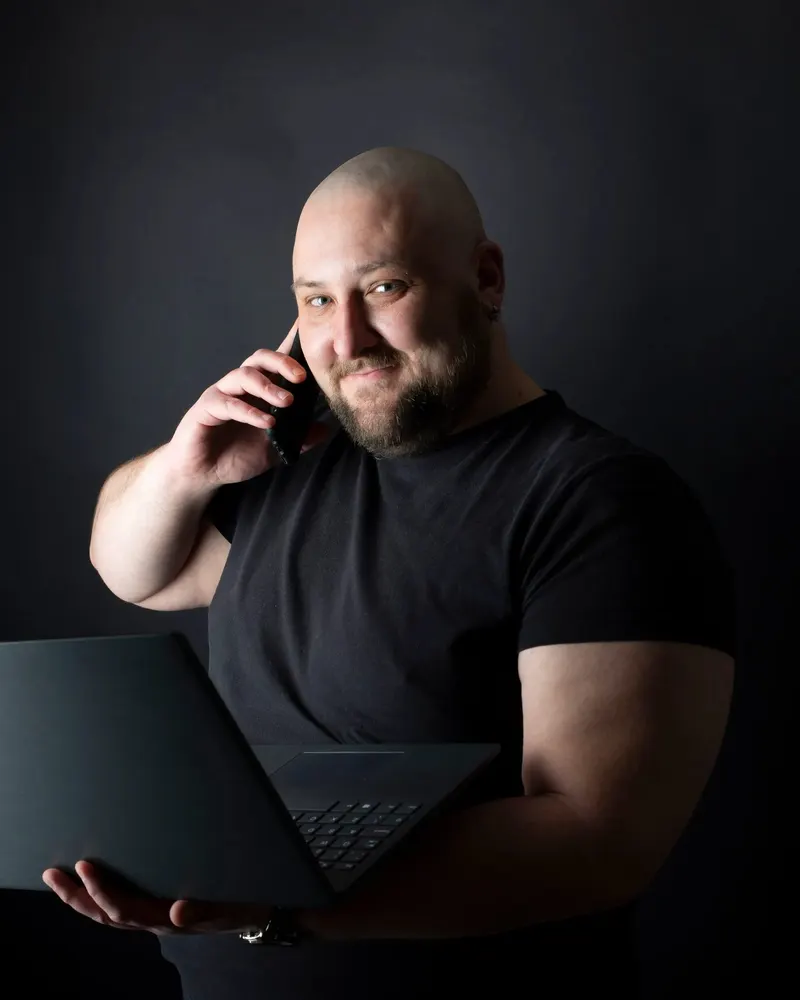 Tomasz Kolpaczek z laptopem i telefonem